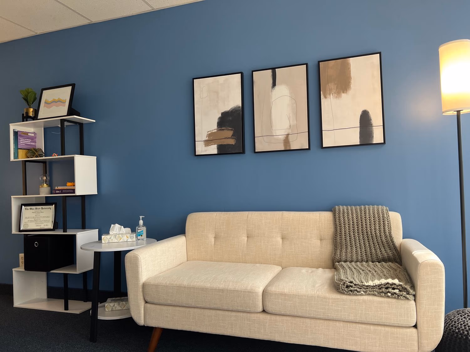 A blue accent wall, artwork, and sofa in Gabby Silone's office at ABHS